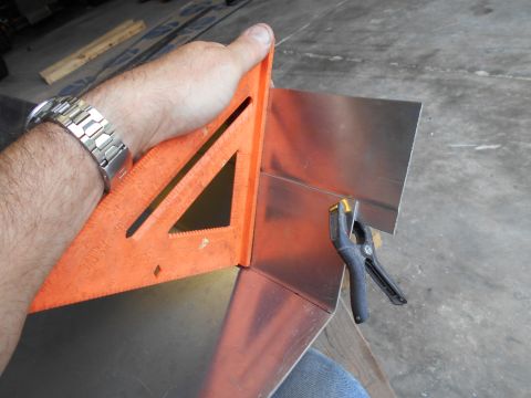 1992 Ford Bronco - A hand uses a speed square to mark a piece of sheet metal, clamped in place for a precise cut.