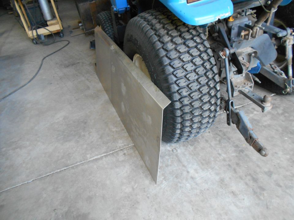 Rear tire of a blue lawn tractor with a metal plate attached to the side