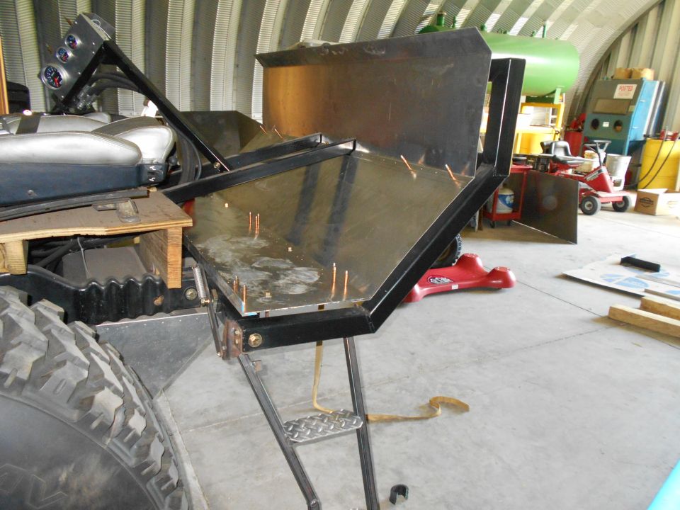 part of a vehicle with custom metal fabrication attached, large tire visible