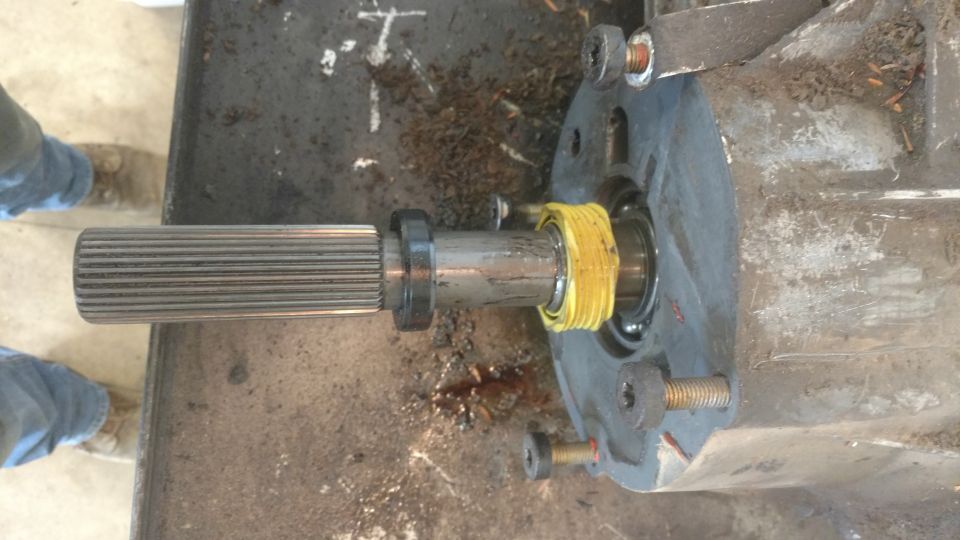 Splined shaft extending from a gray transfer case housing with yellow sealing tape