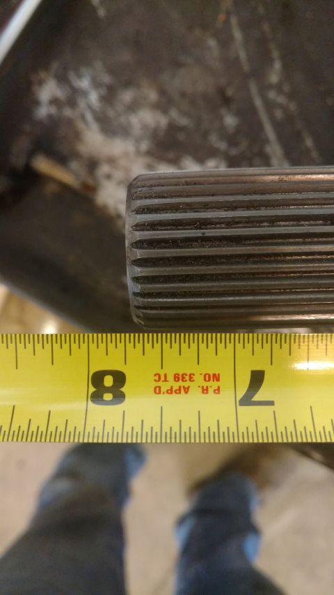 1996 Ford Bronco - A splined shaft is measured with a yellow tape measure, indicating its dimensions for a part upgrade.