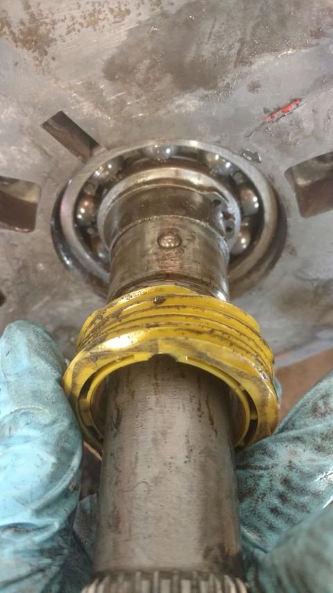 1996 Ford Bronco - Close-up of a bearing assembly with a yellow plastic ring being held by gloved hands.