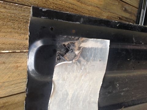 2001 Ford Ranger - A close-up view of a damaged black metal panel, revealing rust and torn material.