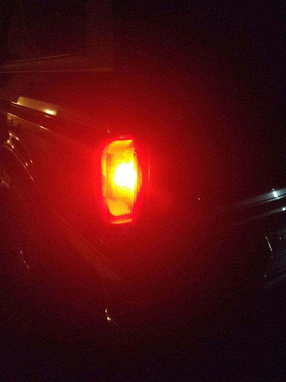 Illuminated red and amber taillight on a vehicle's rear corner at night