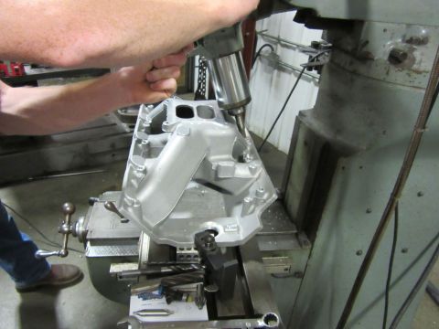 Aluminum intake manifold on a milling machine with a drill bit working on it