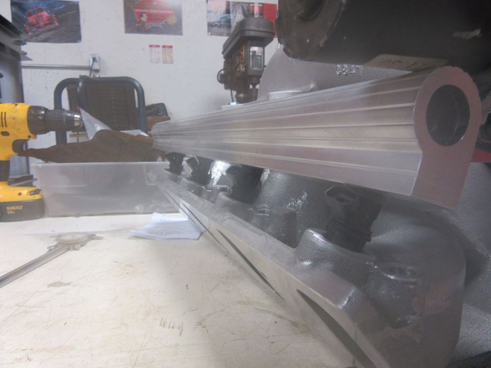 engine intake manifold on workbench with drill and caliper nearby
