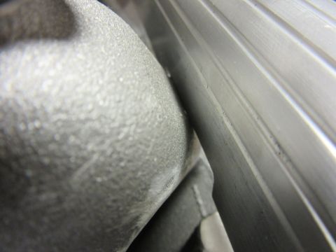 Close-up of a textured metal engine component next to a ribbed metal surface