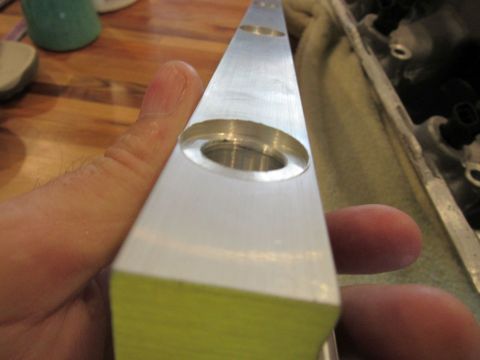 Hand holding a machined aluminum part with two circular holes