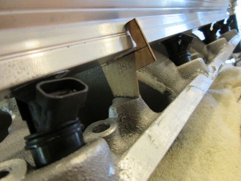Engine intake manifold with injectors and a handwritten tag reading "945"