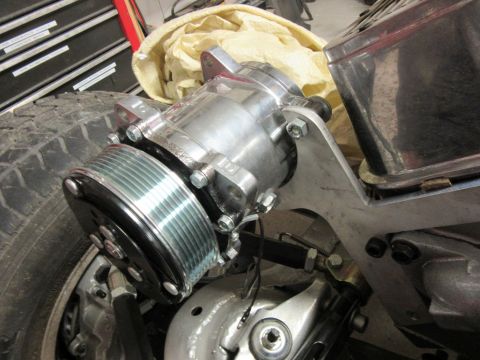 Close-up of a chrome power steering pump with a ribbed pulley attached to a bracket
