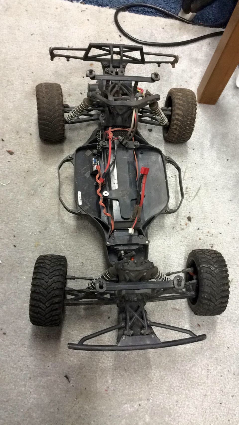RC car chassis with exposed wiring and suspension components, viewed from above