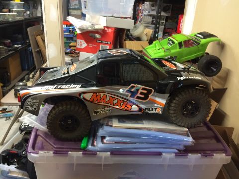 1989 Ford Bronco - Two remote control monster trucks are displayed in a cluttered storage area.