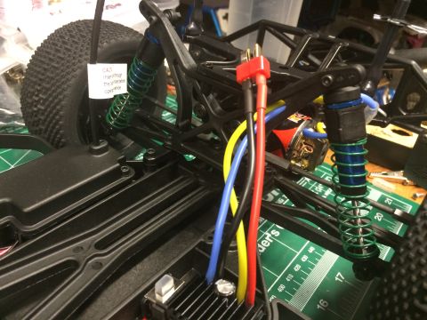 1989 Ford Bronco - RC car chassis with visible wiring and suspension components. A caution note is attached to the tire.