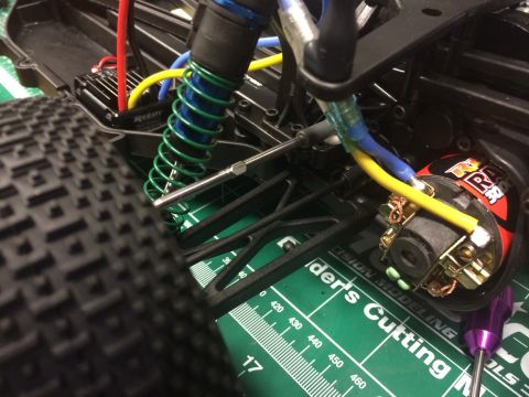 1989 Ford Bronco - Detail of an RC car's suspension system and electric motor, placed on a green cutting mat with measurement markings.