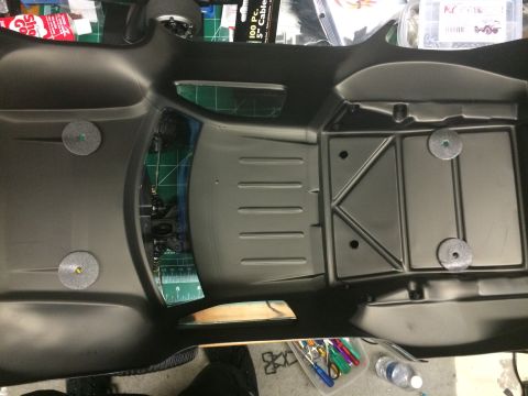 1989 Ford Bronco - The interior of a black RC car body is shown, with a cutting mat and hobby supplies visible in the background.