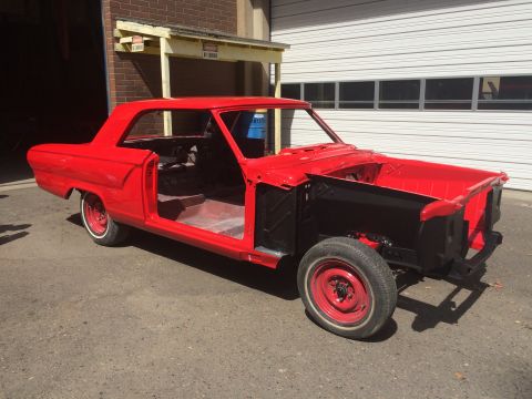 1964 Ford Fairlane - A red 1964 Ford Fairlane body sits outside a garage, undergoing restoration.