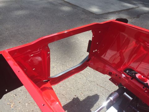 1964 Ford Fairlane - A red painted car frame is shown outdoors, likely undergoing restoration or repair.