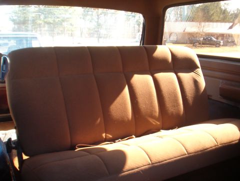 1988 Ford Bronco - Interior view of the rear bench seat in a 1988 Ford Bronco. A second vehicle is visible through the window.