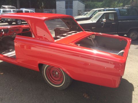 1964 Ford Fairlane - The rear section of a red 1964 Ford Fairlane coupe is shown from a rear quarter angle, with other vehicles in the background.