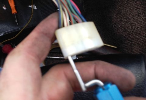 1968 Mercury Cougar - Close-up of a hand holding a wiring harness connector with various colored wires.