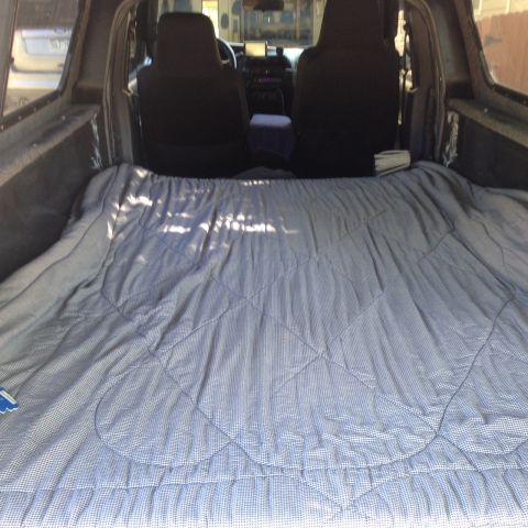 2001 Ford Ranger - Interior view of a truck bed converted into a sleeping area with a blanket.