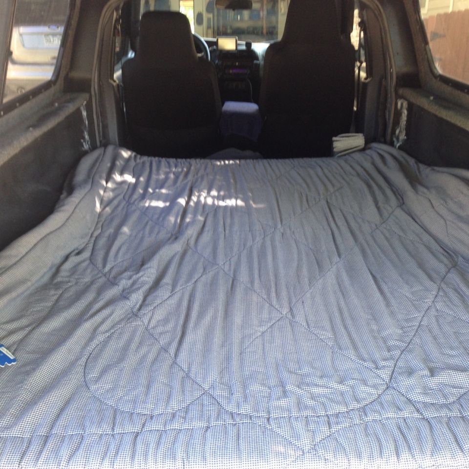 Truck bed interior with a gray and white checkered blanket covering the floor, showing seats and dashboard