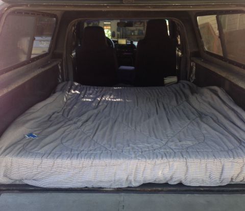 2001 Ford Ranger - The interior of a truck bed is shown, covered by a large sleeping bag, suggesting a makeshift sleeping area.