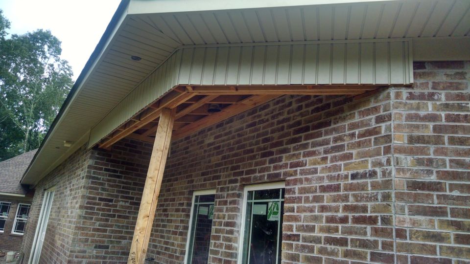Exterior view of a house with brick walls and unfinished porch framing