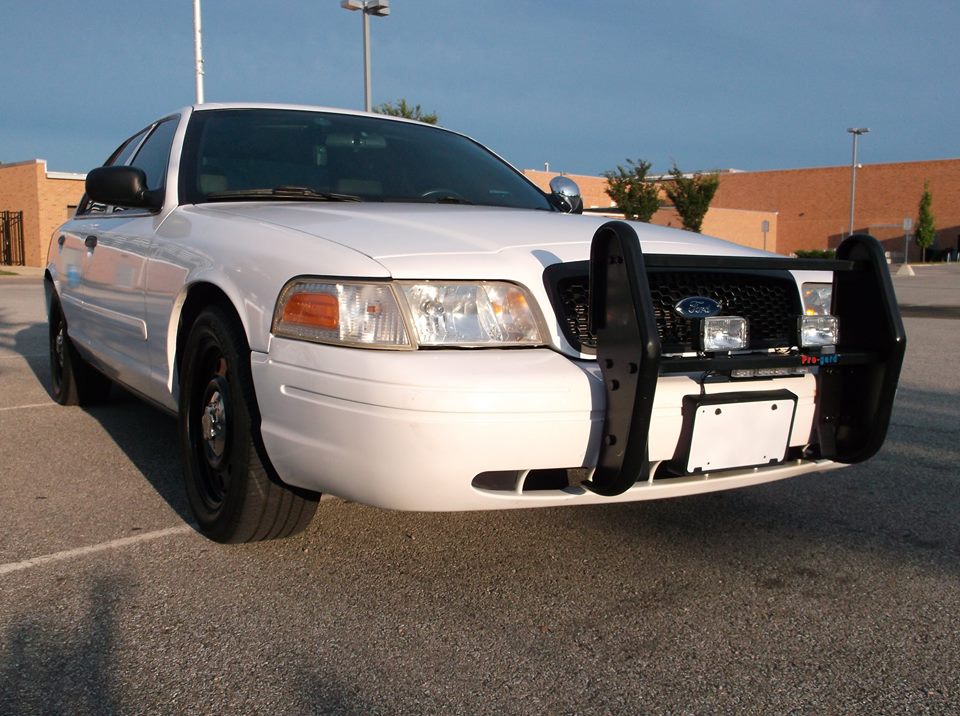 White Ford Crown Victoria police car with a push bar and lights.