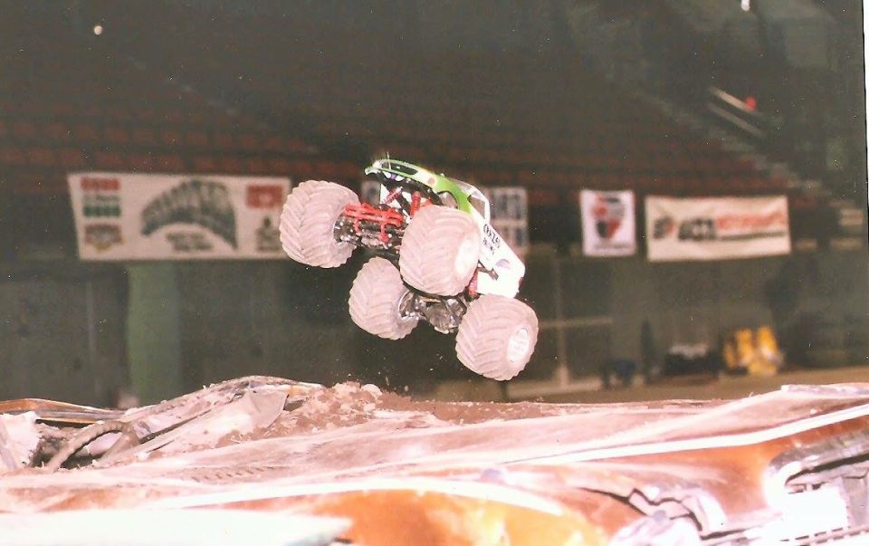 Monster truck jumping over debris in an arena.