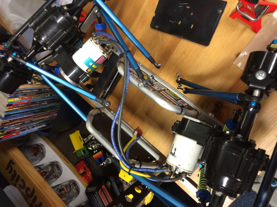 Close-up of RC car chassis with blue suspension arms and drivetrain components.