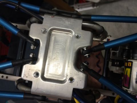 1989 Ford Bronco - A close-up view of the suspension components of a custom vehicle, featuring blue metal rods connected to a silver aluminum plate with visib…
