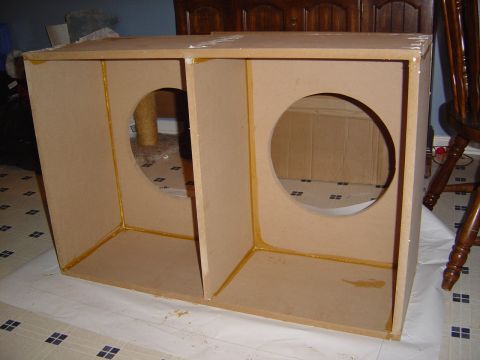 1986 Ford Bronco - A homemade MDF speaker/subwoofer enclosure with two chambers, each featuring a large circular cutout for a driver, sitting on plastic sheet…