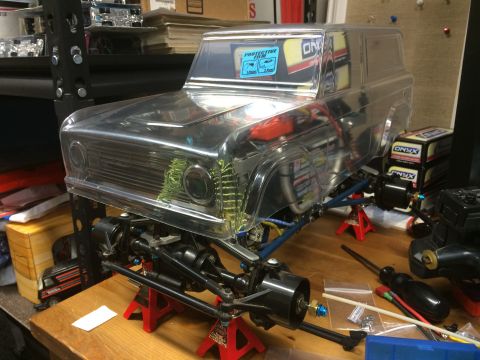 1989 Ford Bronco - A clear plastic body of a 1980s Ford Bronco is shown mounted on a custom off-road chassis with visible suspension components and shocks. Th…