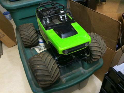 1989 Ford Bronco - A bright green remote-controlled monster truck with large, knobby tires sits on top of a green plastic storage bin. The truck has a black r…