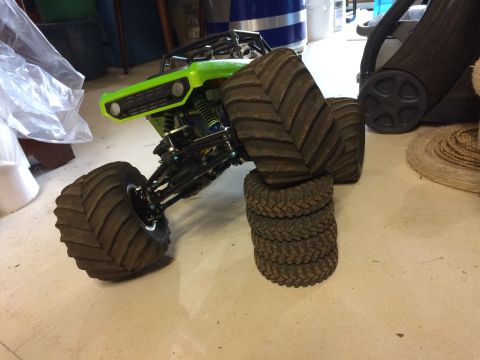 1989 Ford Bronco - A bright green remote-controlled monster truck is shown with its large tires resting on a stack of smaller tires. The truck is positioned o…