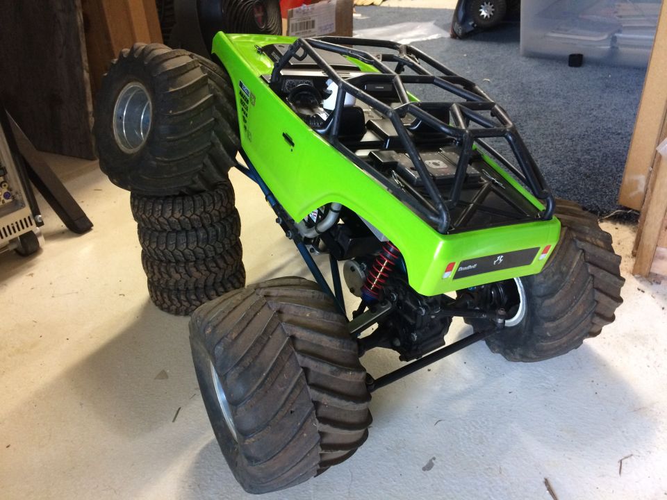Green remote-controlled monster truck with large tires and roll cage.
