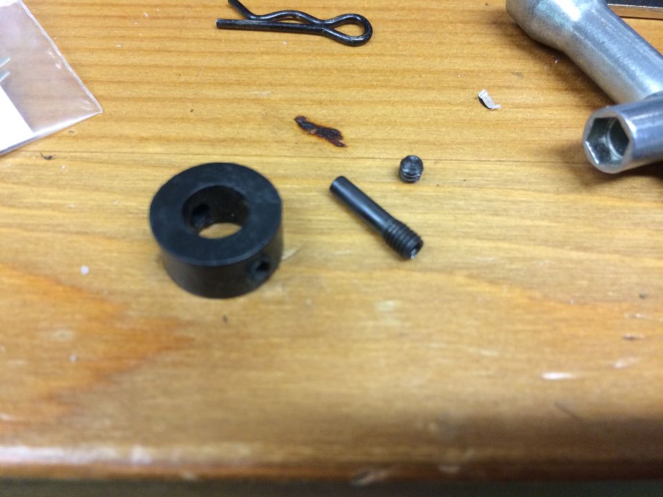 Assorted small metal hardware and a wrench on a wooden table.
