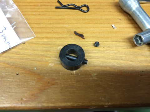 1989 Ford Bronco - A collection of small metal parts, including a black collar with a set screw, a small screw, and a hairpin clip, are laid out on a wooden s…