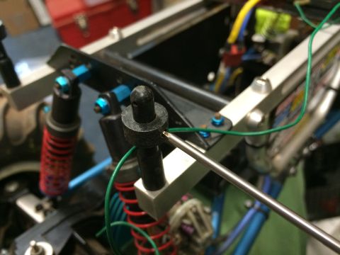 1989 Ford Bronco - A close-up view shows the suspension components of a vehicle, including red coilover shocks with blue mounting hardware. A thin metal rod i…