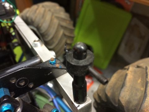 1989 Ford Bronco - Close-up view of a black ball joint assembly with a threaded rod extending from it, mounted on a silver metal chassis. A large, knobby tire…
