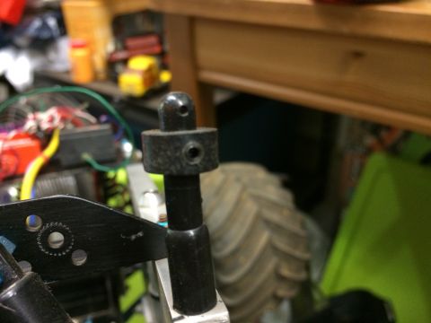 1989 Ford Bronco - A close-up view of a black plastic part with a ball joint on top, mounted on a black metal bracket. The part appears to be a component of a…