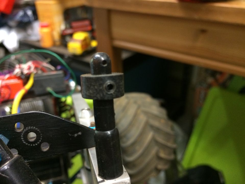 Black plastic part with ball joint on metal bracket, likely from an RC vehicle.
