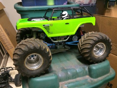 1989 Ford Bronco - A bright green remote-controlled monster truck with large tires and a roll cage is displayed on top of a green plastic container. The truck…