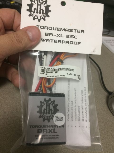 1989 Ford Bronco - A hand holds a package containing a Holmes Hobbies Torquemaster BR-XL ESC, which is a waterproof electronic speed controller.