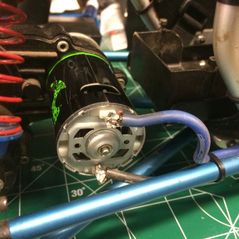 1989 Ford Bronco - Close-up view of a black electric motor with green graphics, showing its connection to blue and black wires. The motor is mounted on a blue…