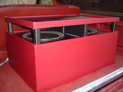 1986 Ford Bronco - A custom red-painted subwoofer enclosure with a raised removable top panel, revealing two round black speaker mounts and internal bracing,…