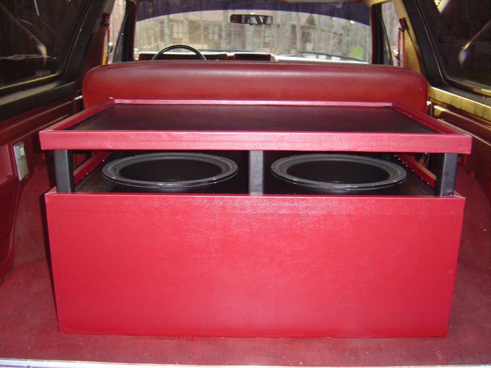 Red custom subwoofer box with two speakers in vehicle cargo area