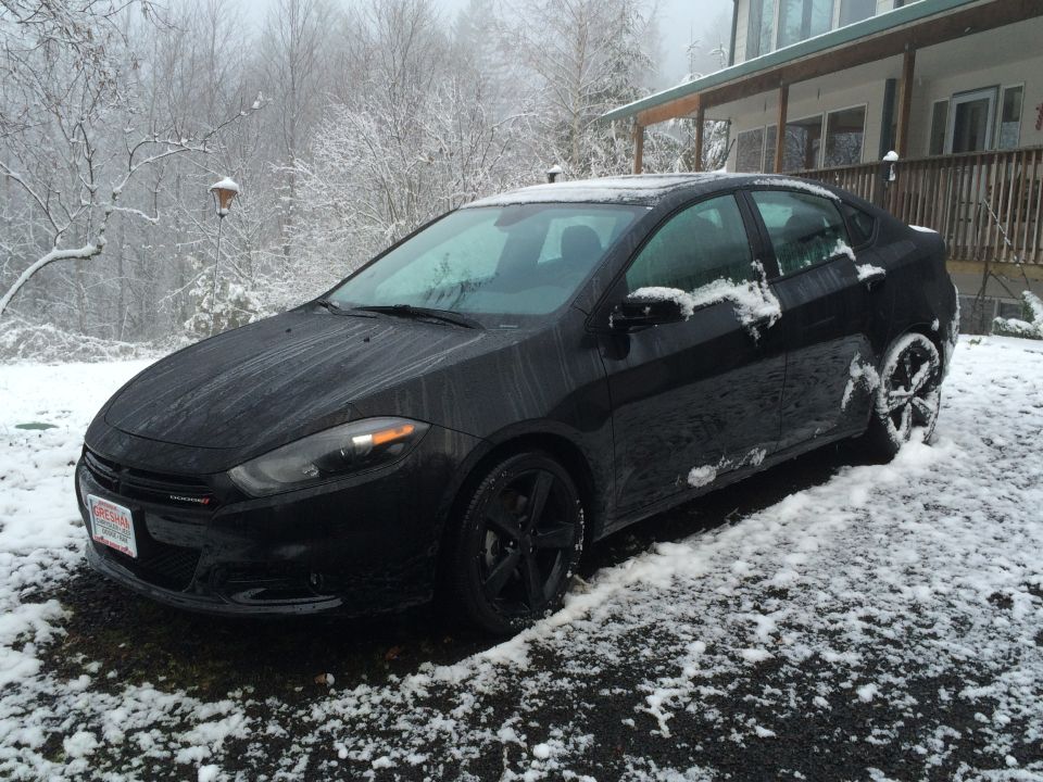 Black 2015 Dodge Dart sedan in light snow.