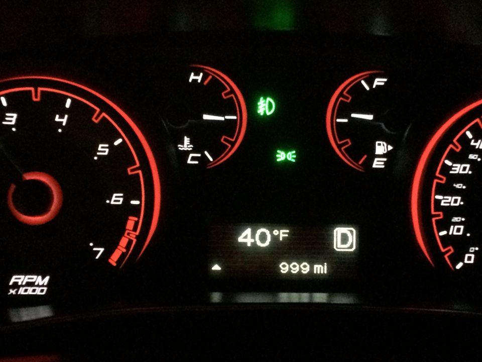2015 Dodge Dart dashboard with red illuminated gauges and digital display showing 40°F and 999 miles.
